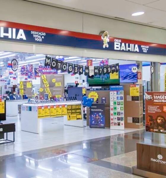 Bright electronics store inside a mall with stacked boxes yellow sale signs and checkout counters in the background