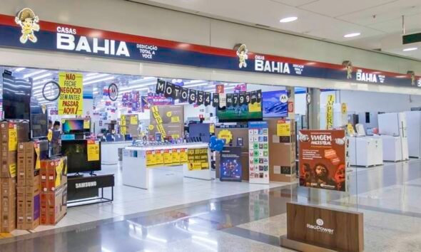 Bright electronics store inside a mall with stacked boxes yellow sale signs and checkout counters in the background