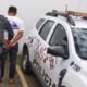 Military police officer cuffs a man next to a white police SUV with a rooftop light bar in a parking area